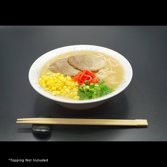 hakata ramen with additional condiments and corn in bowl with chopsticks laid in front on a rock